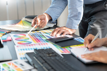 graphic designer team working on web design using color swatches editing artwork using tablet and a...