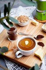 KETOGENIC KETO DIET DRINK. Coffee and cocoa mixed with ghee. Cup of bulletproof coffee with cocoa and ingredients on wooden background