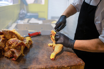 Butcher prep cuts chicken on wooden cutting board. Fresh and healthy food preparation concept