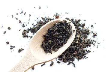 Wooden spoon of dry green tea isolated on white background