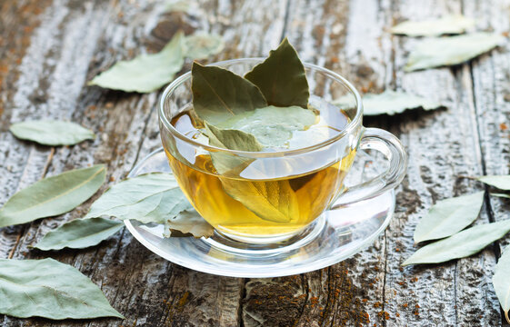 Cup of natural bay leaf herbal tea on wooden table