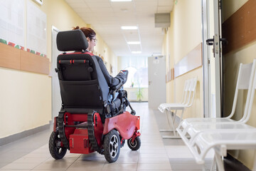 Caucasian woman in electric wheelchair in university corridor.