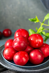 Chinese or Korean red plum in a plate on the table closeup. Summer or autumn harvest
