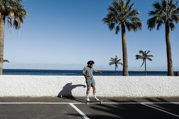 African american man riding longboard with beach in the background - Focus on face