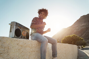 African american man listening music with vintage boombox stereo outdoor on the beach - Focus on...