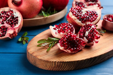 Delicious ripe pomegranates on blue wooden table, closeup