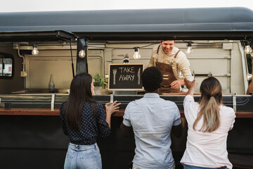 Multiracial people ordering takeaway food at counter in food truck outdoor - Focus on take away sign