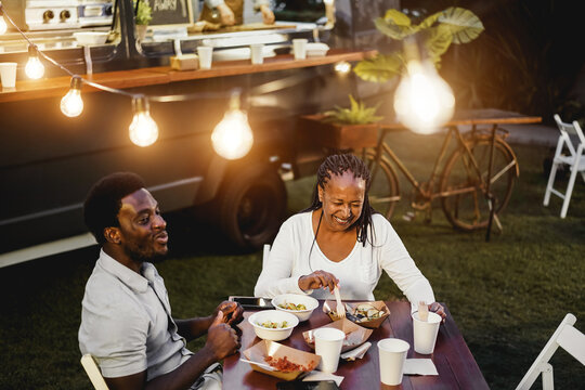 Black Mother And Son Eating And Drinking Healthy Food At Food Truck Restaurant Outdoor - Focus On Senior Woman Face