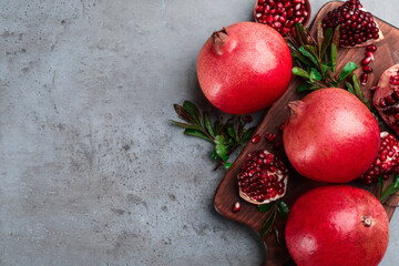 Delicious ripe pomegranates on grey table, flat lay. Space for text