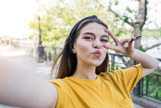 Young and beautiful caucasian girl make a selfie on a smartphone and showing a gesture of peace and a kiss