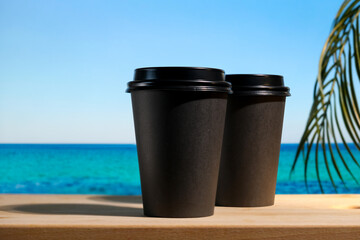 Obraz premium Two takeaway coffee or tea containers on summer tropical background. Coffee shop, beach bar concept.