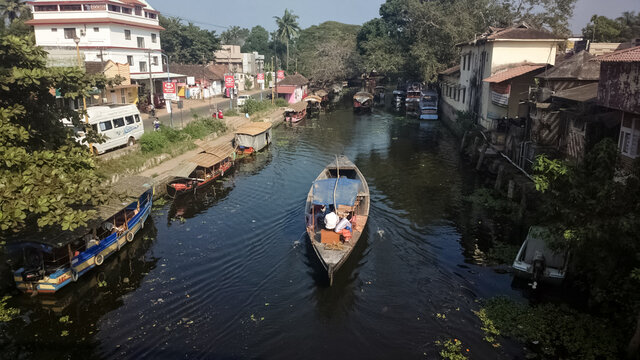 A wooden ferry boat passing through a backwaters canal in the town of Alleppey.
