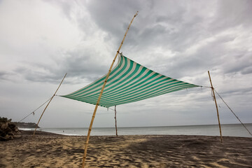 A low angle shot of a canopy tent on the beach with a cloudy sky above in Varkala in Kerala, India.
