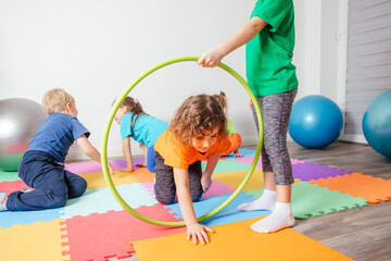 Curly girl crawling on colorful floor through hula hoops © oksix
