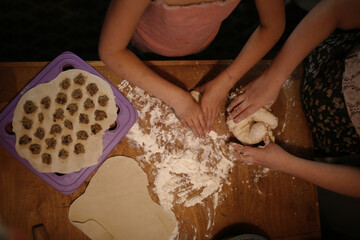 Children in the kitchen sculpt prepare dumplings, evening photo, dark style