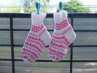 Knitted warm wool socks white and pink color hanging and dry on balcony after wash in a sunny day