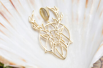 Brass metal pendant on natural background in the shape of deer animal