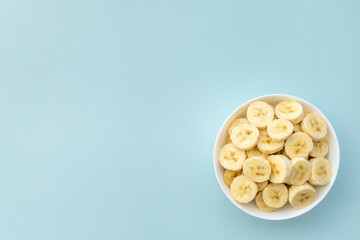 Many banana slices in white bowl. Top view