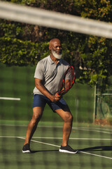 Obraz premium Senior african american man playing tennis on tennis court
