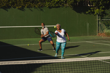 Senior african american couple playing tennis on tennis court