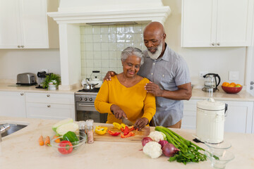 Senior african american couple cooking together in kitchen smiling - Powered by Adobe