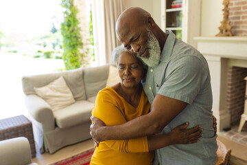 Senior african american couple embracing with eyes closed in living room - Powered by Adobe