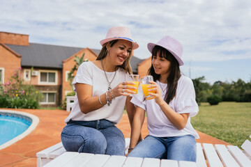 Mother and daughter enjoying the day drinking orange juice.