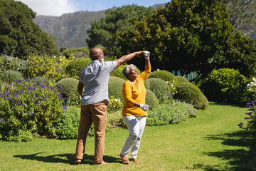 Senior african american couple spending time in sunny garden together dancing