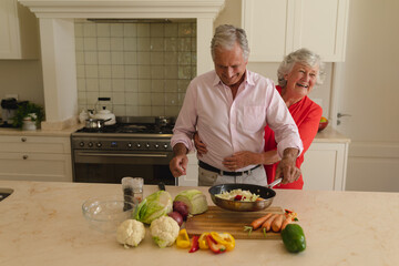 Senior caucasian couple cooking together and smiling in kitchen