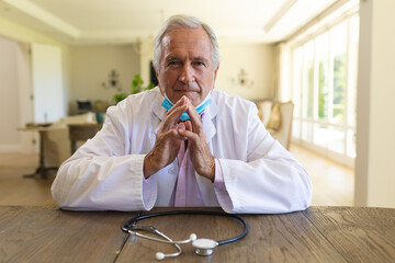 Senior caucasian male doctor wearing face mask having a video call