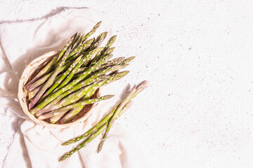 Ripe asparagus in a wicker basket on light plaster background