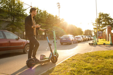 Transportation ecology. Green sustainable mobility Young man unlocks an e-scooter with his mobile...