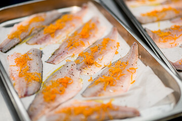 selective focus on slices of fish with grated carrots on baking sheet