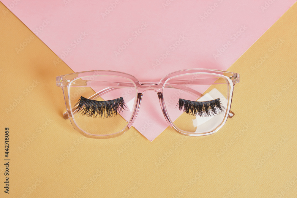 Wall mural eye glasses on a concrete podium on a pink and beige background, trend composition, black stylish eye glasses,