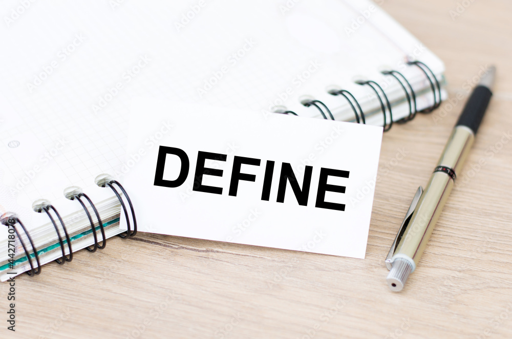 Fototapete Define word on a white business card on a table next to a notepad on rings and a pen