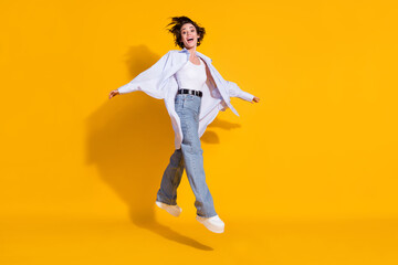 Fototapeta na wymiar Full length body size photo of happy female student jumping stepping forward white shirt isolated on vivid yellow color background