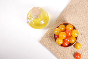 colorful cherry tomato and cooking oil in jar on white background 