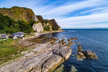 Fototapeta na wymiar Northern Ireland, UK. Atlantic coast with cliffs, Causeway Coastal Route, houses, camping and geological formation of rocks at Garron Point. Aerial view at sunrise