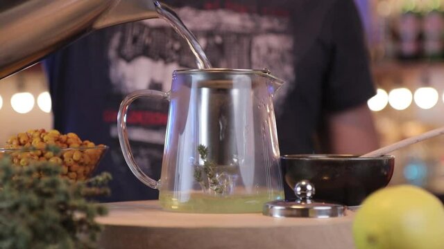 a man pour hot water over the herbs to make tea