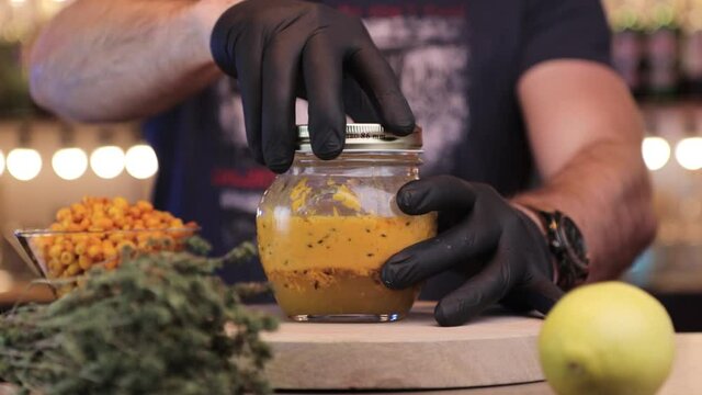 a man closes a jar filled with sea ​​buckthorn
