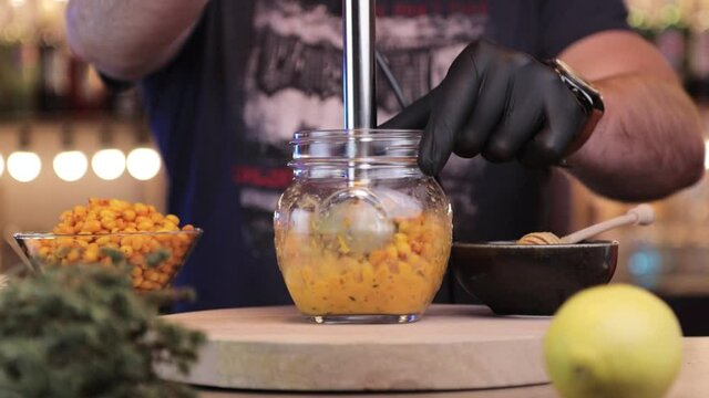a man grinds sea buckthorn with blender