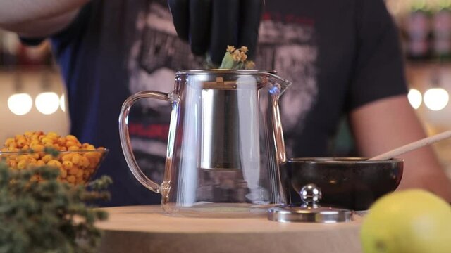 a man put herbs in a teapot