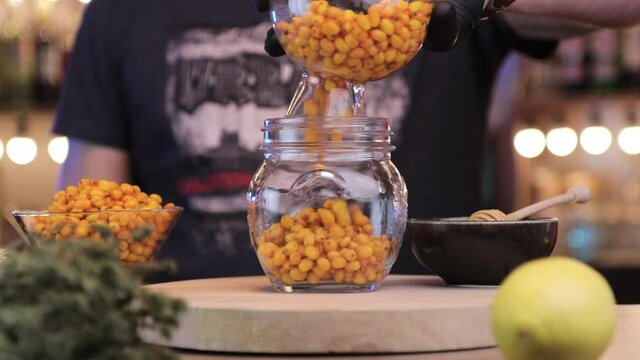 a man pours sea buckthorn into a jar