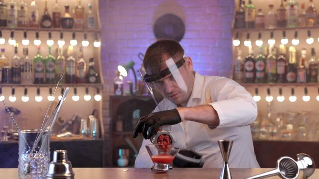 a man in a bar squeeze the tomatoes to make tomato juice