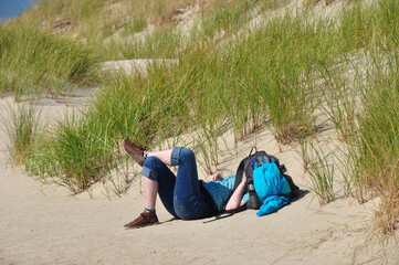 Das Nickerchen in den Dünen: Eine junge Frau ruht sich von der Wanderung aus. 