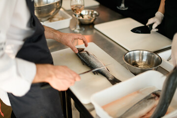 chef cuts fresh fish on white board in the kitchen table.
