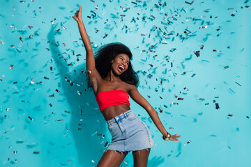 Photo of attractive young dark skin woman dance fall confetti festive party summer isolated on teal color background