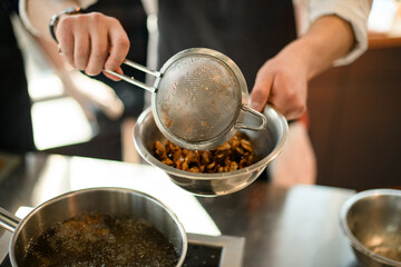 close-up of a sieve in the hands of a male chef.
