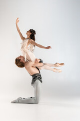 Young couple of ballet dancers in ancient Rome costumes dancing on white studio full of light. Historical character, classical art