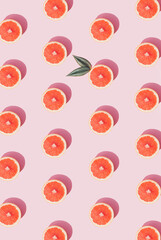 Summer sunlight pattern made with bright grapefruit on a pastel pink bakground. Creative flat lay.